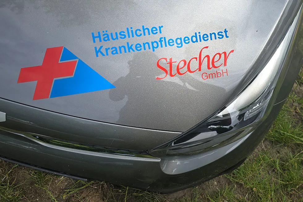 Nahaufnahme der Firmenbeschriftung auf einem Dienstfahrzeug des Pflegedienstes.